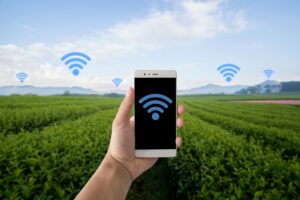 Mano sujetando un movil en el campo con señales wifi por todos lados.