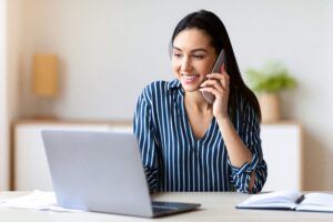 Mujer hablando por teléfono mientras mira al ordenador