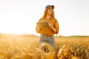 Mujer con gorra sujetando una tablet en el campo
