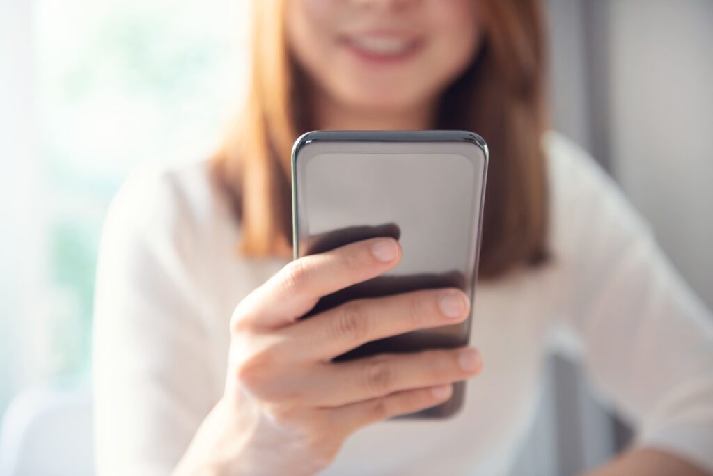 Mujer sonriendo mientras usa el móvil