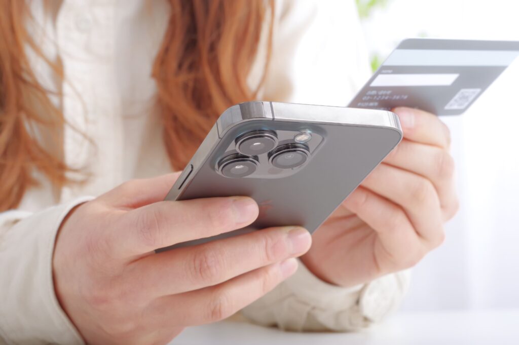 Mujer sujetandio un móvil y una tarjeta bancaria