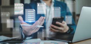 Hombre con un ordenador y móvil y símbolos de herramientas de gestion online