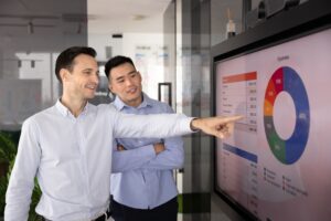 Un hombre enseñándole a otro una infografía en una tele