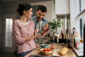 Un hombre y una mujer en la cocina mientras miran el móvil