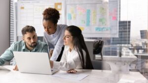 tres personas hablando mientras miran la pantalla del ordenador